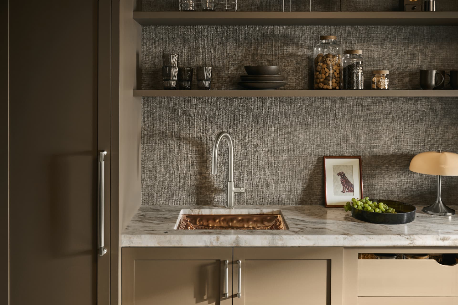 Moody wet bar with hammered copper sink, grasscloth wall and open shelving