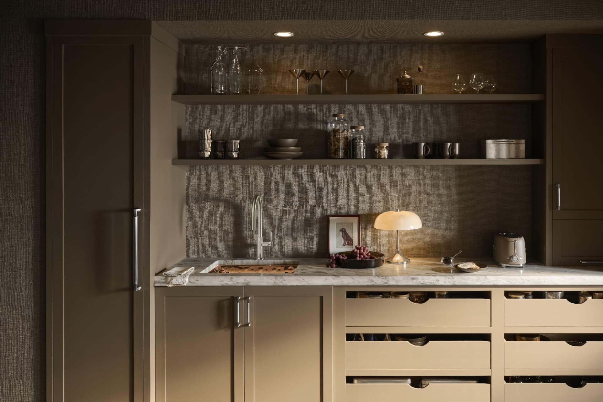 Butler's pantry in warm olive cabinetry with marble counter, open shelving and a glowing dome lamp