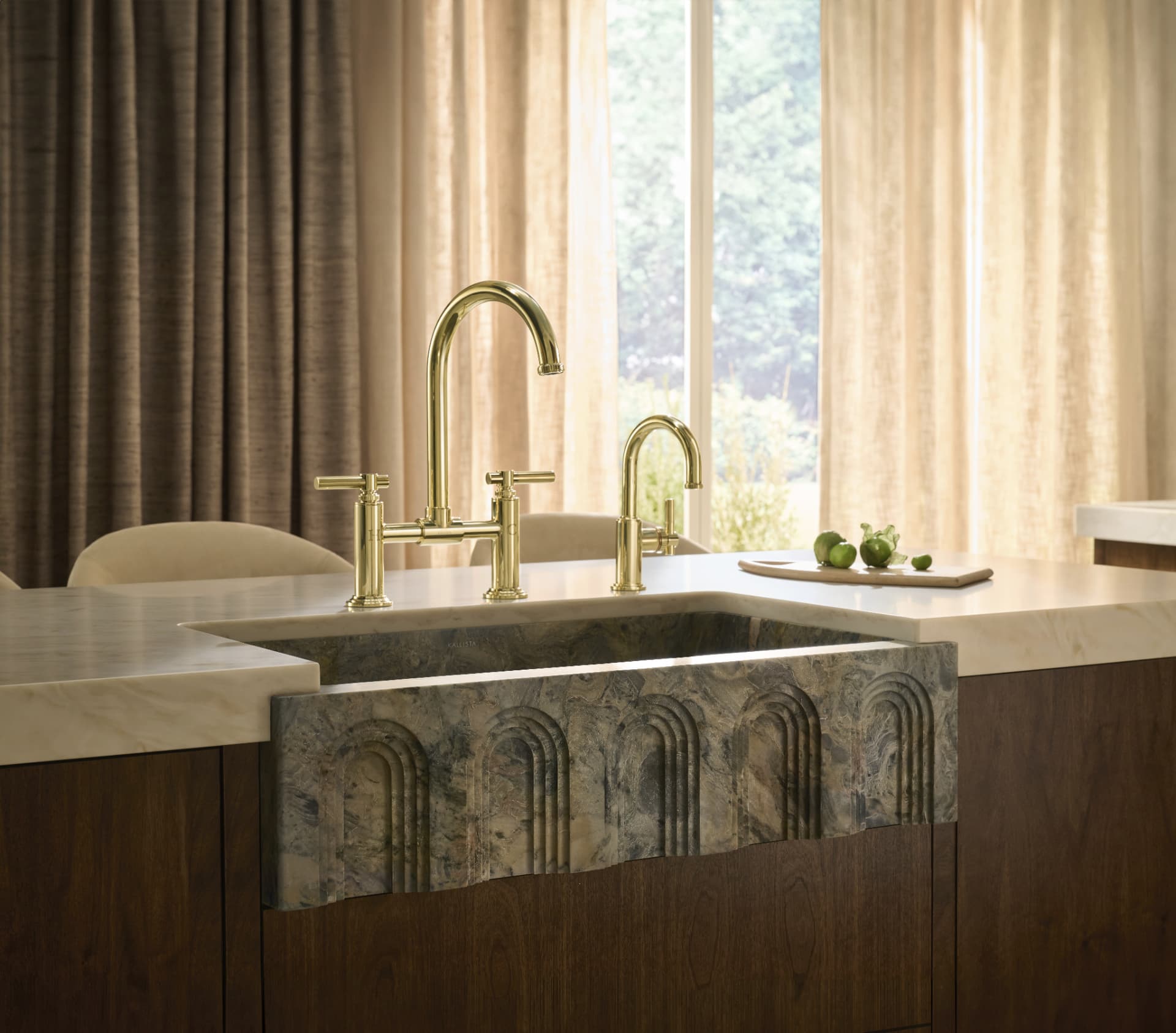 Carved stone apron-front sink with unlacquered brass bridge faucet