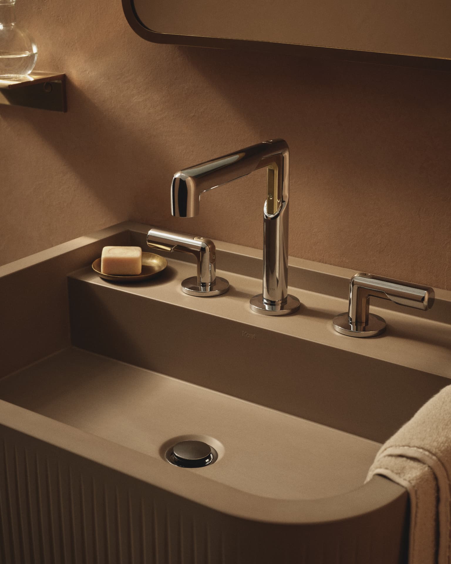 Warmly lit Kallista sink with polished faucet and lever handles
