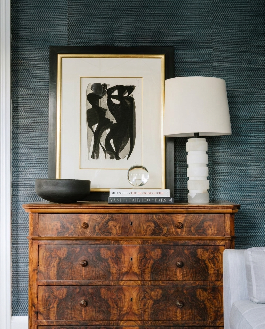 Framed abstract figure study and alabaster lamp on a burl wood chest