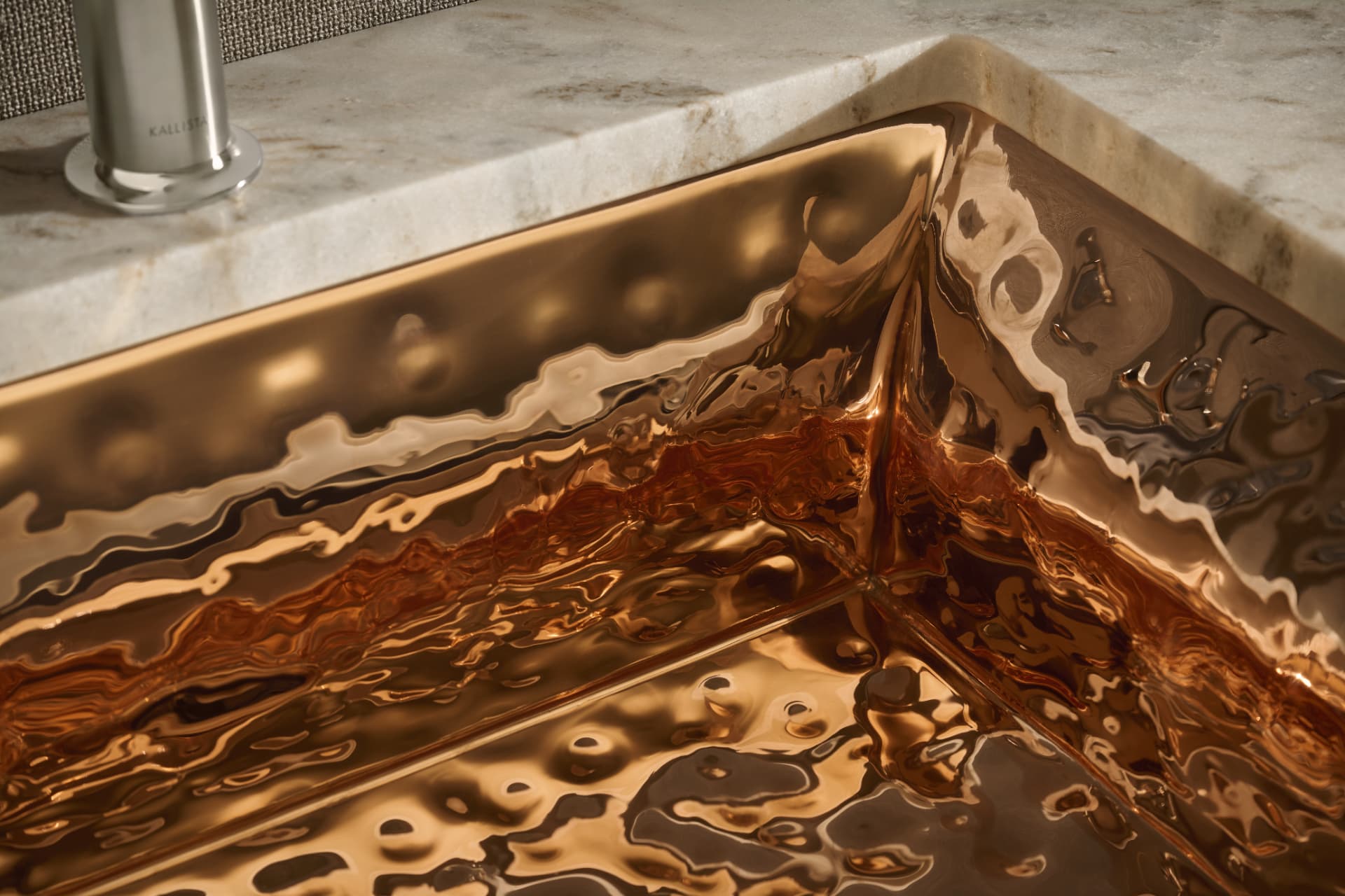 Hammered copper sink detail set into veined marble