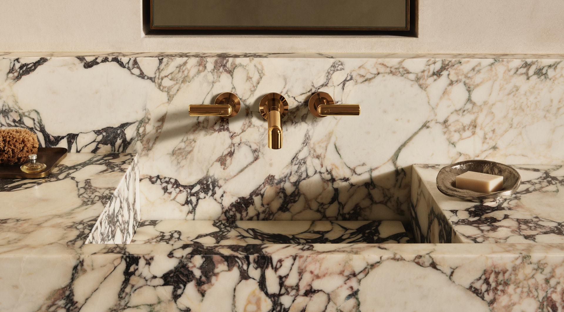 Overhead view of a Calacatta marble sink with sculptural brass wall-mount faucets