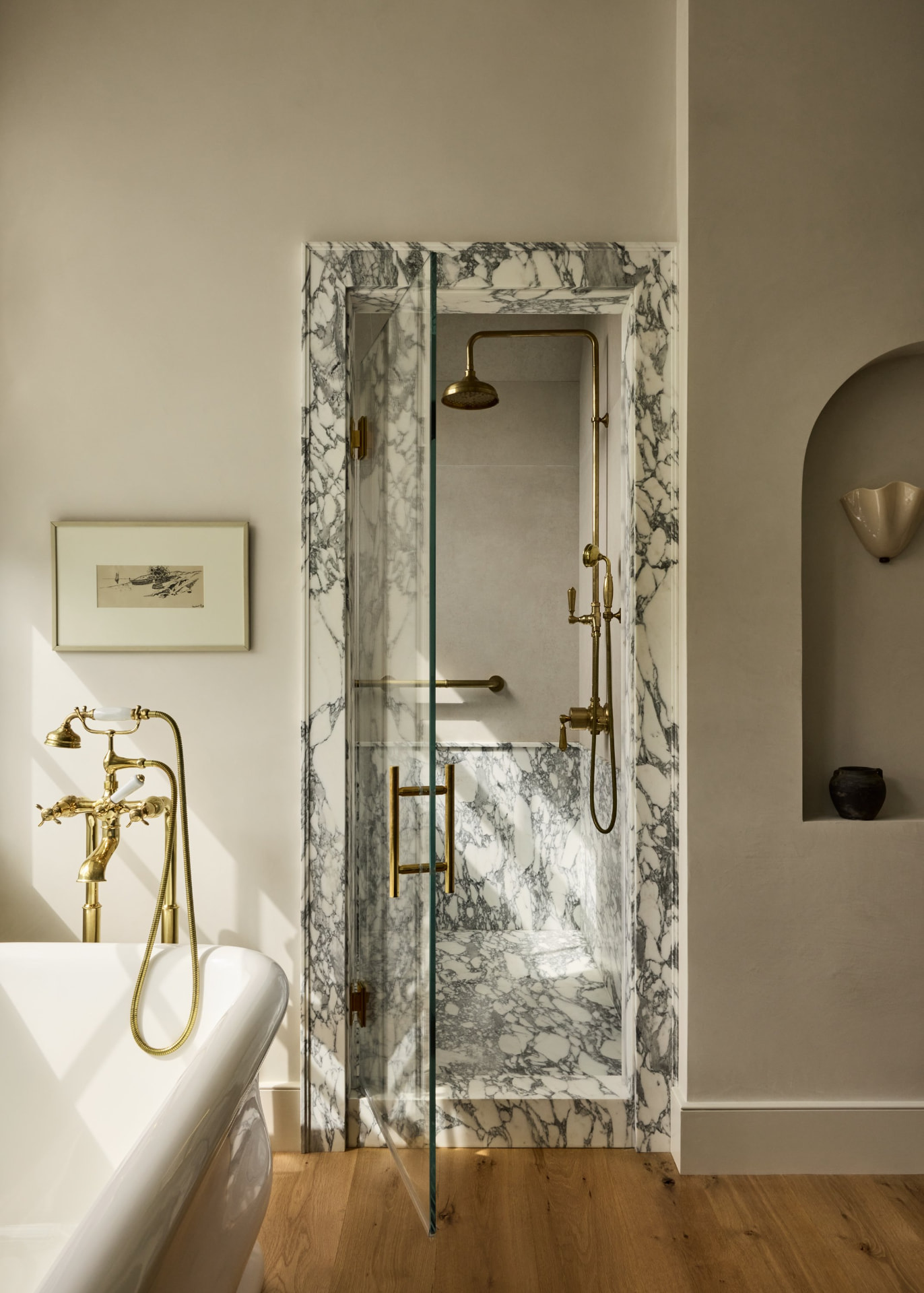 Primary bathroom with marble-clad shower, freestanding tub and brass fixtures