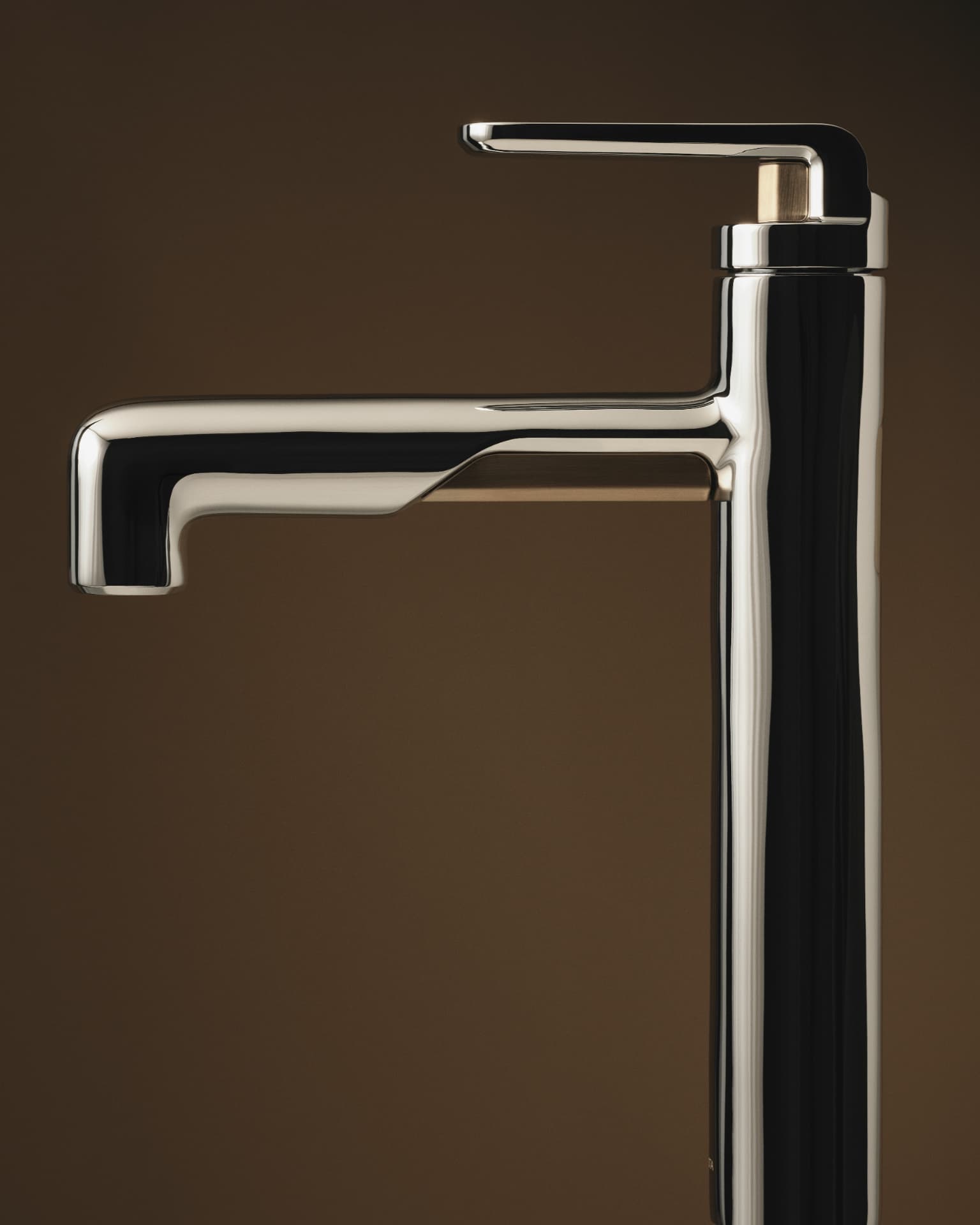 Polished Kallista faucet shown in profile against a warm brown ground