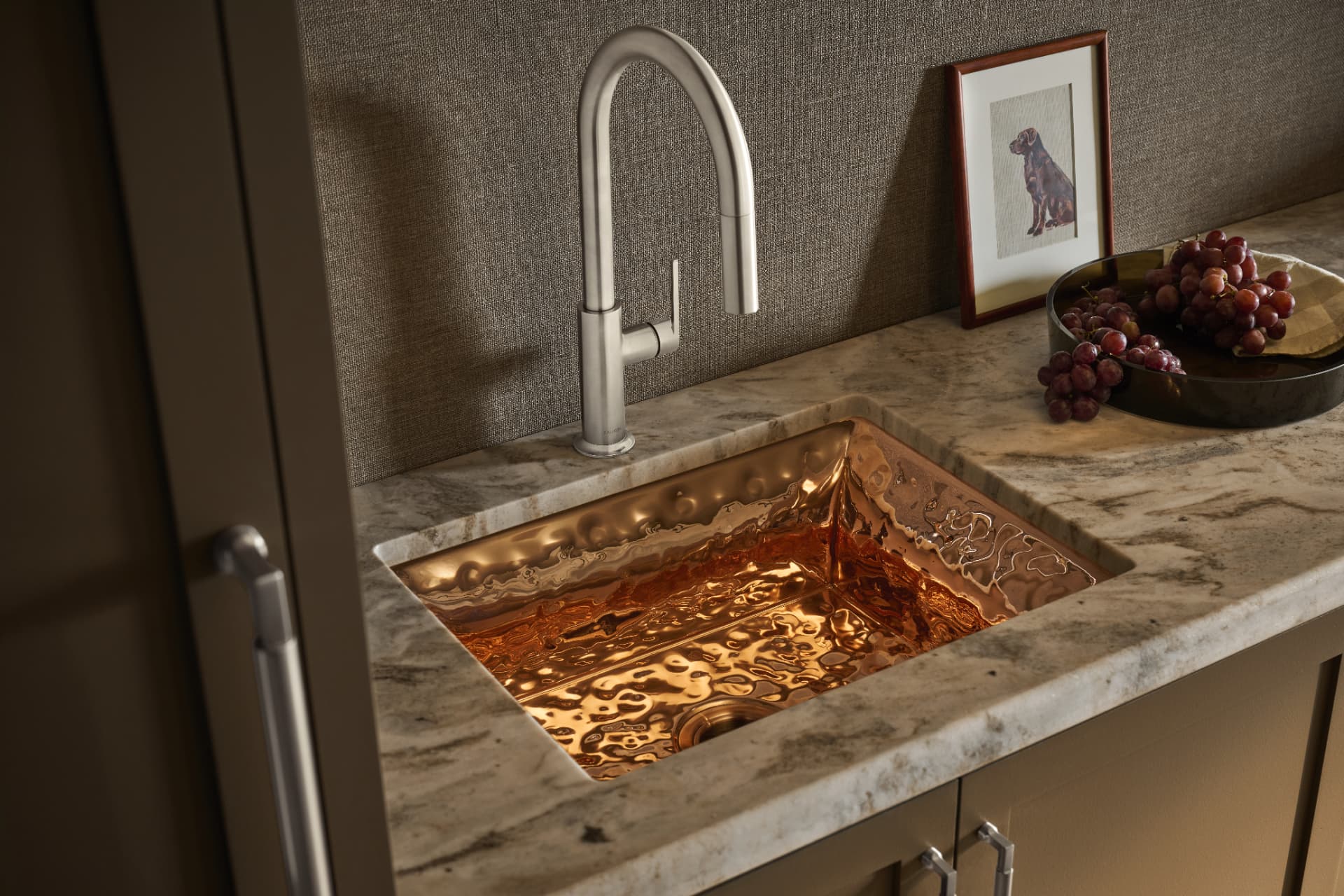 Hammered copper bar sink set into veined marble with brushed nickel faucet